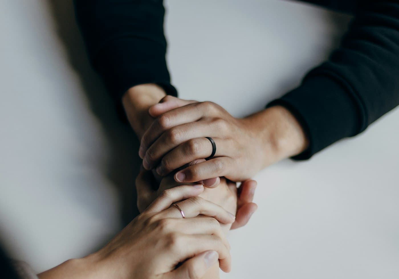 Two people’s hands resting together across a table during a conversation
